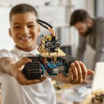 photo d'un enfant qui joue avec un robot et un adulte en arrière plan