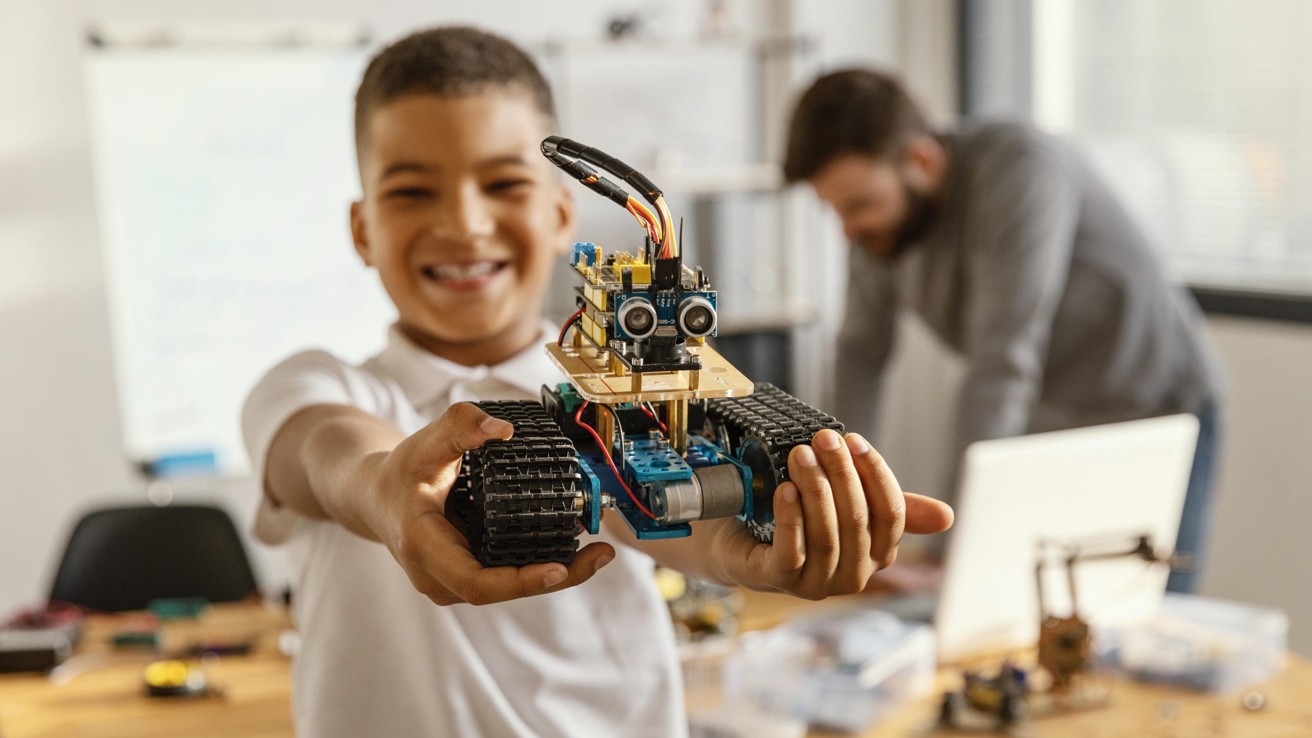 photo d'un enfant qui joue avec un robot et un adulte en arrière plan